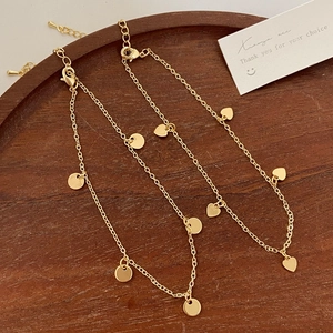 Elegant gold-plated chain bracelet set with round and heart pendants on wooden tray