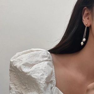Gros plan d'élégantes boucles d'oreilles pompons dorées avec perles d'eau douce