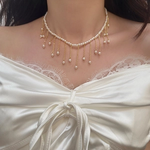 Elegant pearl choker necklace with gold fringe tassels shown on a female model neck