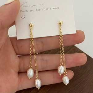 Détail des boucles d'oreilles à double chaîne dorée avec perles d'eau douce baroques