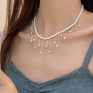 Elegant pearl tassel necklace featuring golden chains worn by a model in a luxury setting