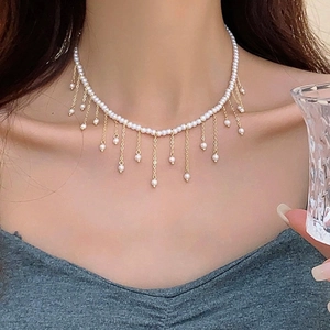 Detail of elegant pearl necklace with gold tassels worn on neck for a luxury aesthetic