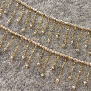 Close-up of gold tassel fringe with small white pearls on elegant grey fabric