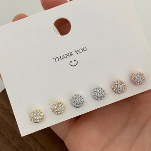 Detailed view of three pairs of pavé disc stud earrings in gold, silver, and rose gold