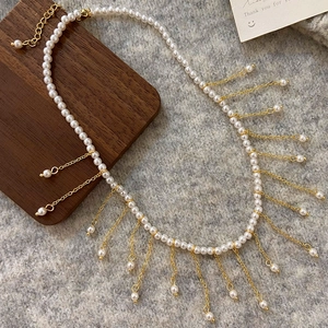 Detail of elegant pearl necklace with gold fringe tassels on a soft textured background