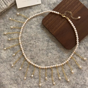 Elegant pearl tassel necklace with gold chains on knit fabric for a luxury French look