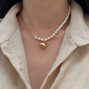 Détail macro d'un collier en perles baroques avec pendentif cœur doré