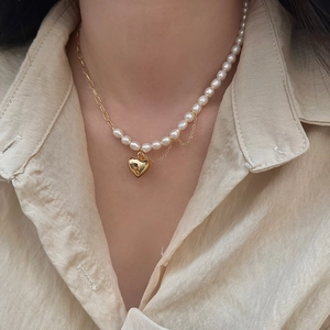 Gros plan du collier de perles baroques avec pendentif cœur doré sur chemise