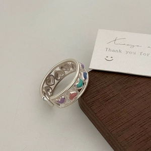Detail of hollow heart rings with colorful enamel and bead edges on a neutral tabletop