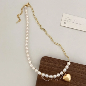 Détail du collier de perles baroques et chaîne dorée avec un pendentif cœur miroir
