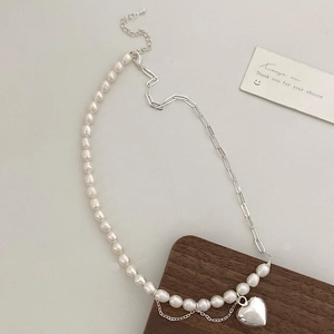 Détail du collier de perles baroques avec pendentif cœur et franges métalliques