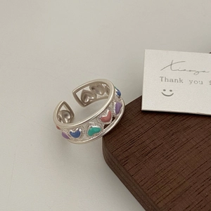 Detail of adjustable ring featuring colorful enamel hearts on an openwork metal band