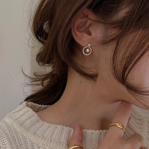 Detail of round pearl earring with micro-set diamonds and a gold ring on a model