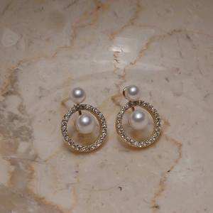 Detail view of gold hoop earrings featuring micro-pave cubic zirconia and double pearls