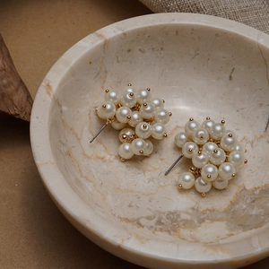 Elegant cluster pearl stud earrings with gold accents on a marble tray background