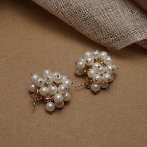 Detail shot of cluster pearl earrings with gold base on vintage linen background