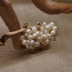 Detailed close-up of cluster pearl stud earrings on a natural wood branch display