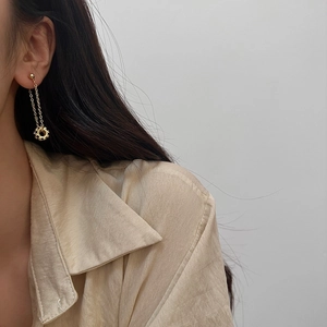 Close-up of elegant gold tassel earrings with round gear pendant on a female model