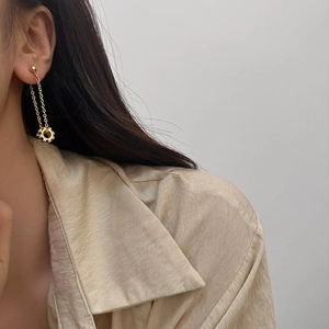 Elegant gold long chain drop earrings with hollow sunburst pendant on a model