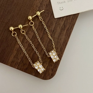 Macro shot of long gold tassel earrings with micro-set zircon on dark wood surface