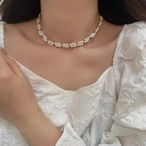 Détail du collier de perles double couche avec des perles dorées sur un cou