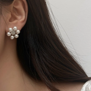 Detailed close-up of a French style floral pearl stud earring with a diamond center