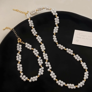 Ensemble collier et bracelet en perles avec billes dorées sur un plateau de présentation