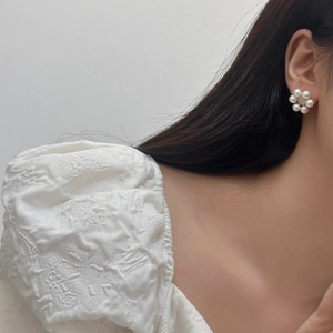 Detailed close-up of a French style floral pearl earring worn on a model's ear