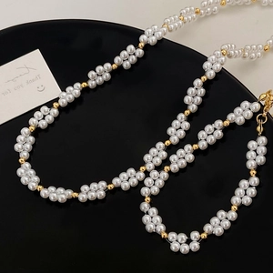 Collier élégant de perles blanches et billes dorées sur un plateau circulaire noir