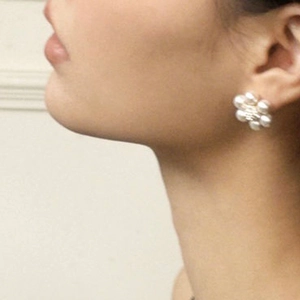 Close-up of French vintage flower pearl stud earrings worn by a model in soft lighting