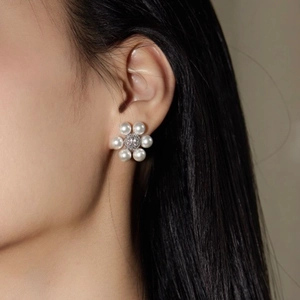 French floral pearl stud earrings featuring a micro-pave center on female model
