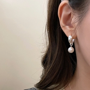 Close-up of minimalist silver hoop earrings with elegant white pearls worn on ear