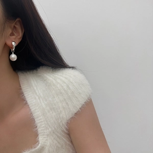 Close-up of minimalist silver pearl drop earrings worn by a model in soft lighting