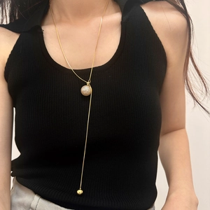 Adjustable gold Y-shaped pearl necklace on black knit top for elegant styling