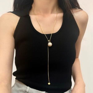 Detailed view of the gold adjustable pearl necklace chain worn by a model