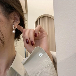 Close-up of minimalist silver hoop earrings featuring a single round white pearl pendant