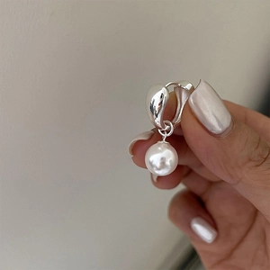 Macro shot of silver pearl hoop earrings featuring thick hoops and high-luster white pearls