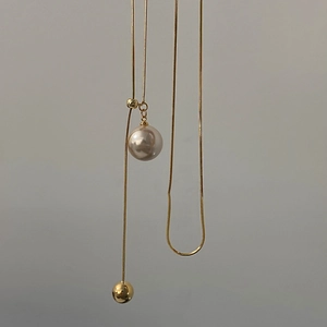 Detail of adjustable gold snake chain with large pearl and gold bead pendant