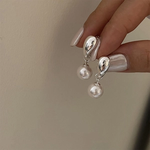Close-up of minimalist silver water drop earrings with round white pearls held in hand