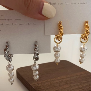 Detail of twisted rope hoop earrings with pearl pendants in gold and silver finish