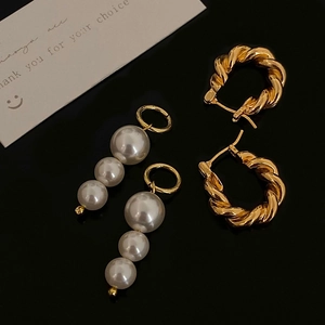 Elegant gold twisted C-hoop earrings and triple pearl drop pendants set on dark background