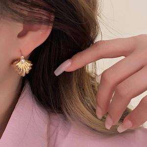 Close-up of vintage gold scallop earrings with central pearl on ear model