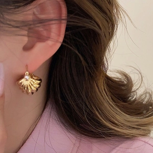 Close-up of vintage French gold shell earrings with a central pearl on a model