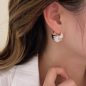 Detailed close-up of ribbed silver C-hoop earrings with pearl accent worn by a model