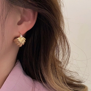 French vintage gold shell earrings with pearl accent worn by a model in a close-up shot