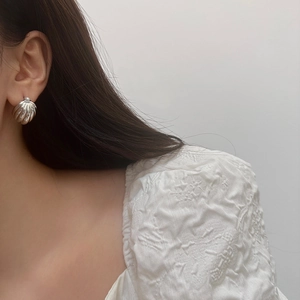 Macro close-up of a silver spiral shell earring worn with a stylish French retro look