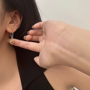 Elegant geometric gold tassel drop earrings featuring a woven metal knot and long chain