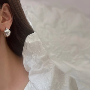 Macro view of vintage silver scallop shell earrings on model showing French retro style