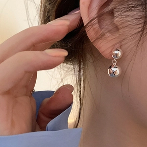 Close-up of minimalist silver double ball earrings with mirror-polished finish on model