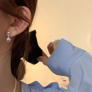 Minimalist silver ball drop earrings paired with a delicate pearl necklace on a model